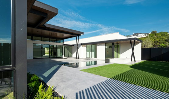 Modern house with patio, green lawn, and blue sky.