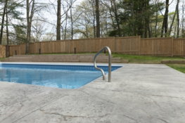 a-pool-is-near-a-wooden-fence-.jpg A pool is near a wooden fence.