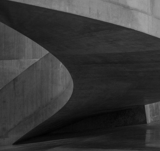 a-black-and-white-photo-of-a-curved-concrete-structure.jpg a black and white photo of a curved concrete structure