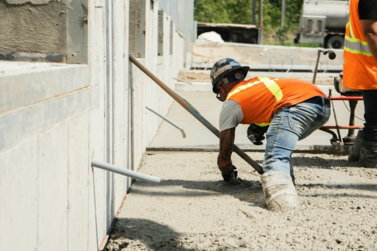 two men in orange vests working on a building