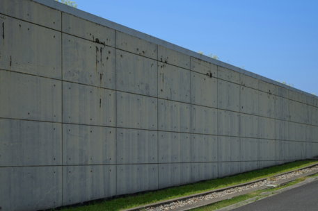 Concrete wall stretches along a grassy slope.