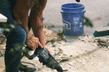 man in blue shirt and black shorts holding black and blue power tool