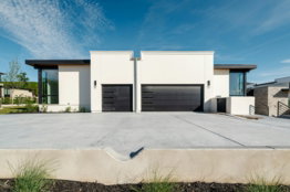 Two contemporary white homes with black garage doors.